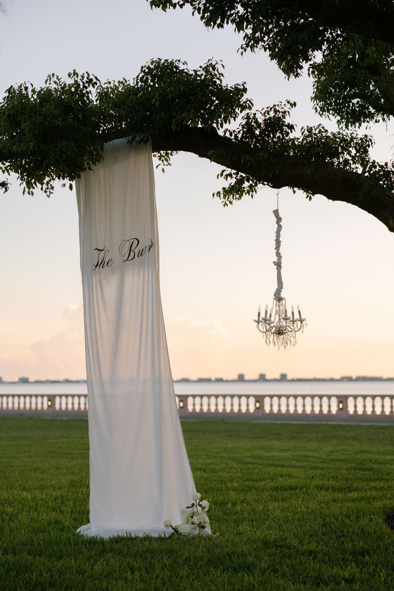 Elegant white sign hanging from large oak tree for wedding ceremony at New College in Sarasota, Florida